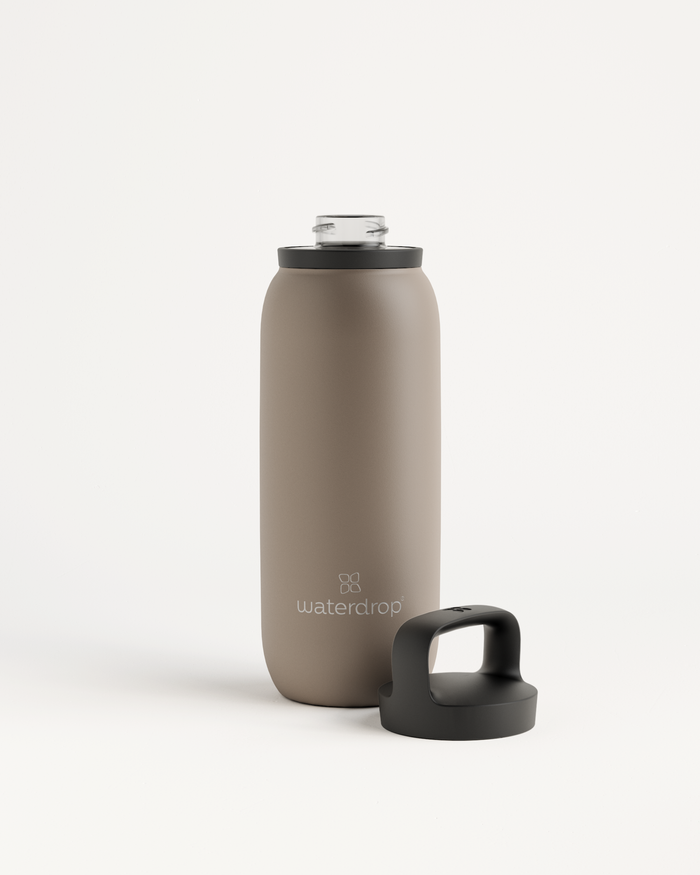 De All-Purpose Thermo · Dop met drinktuit is een herbruikbare, geïsoleerde waterfles van taupe kleur met een schroefdop en lusgreep, perfect voor het langdurig koel houden van dranken.