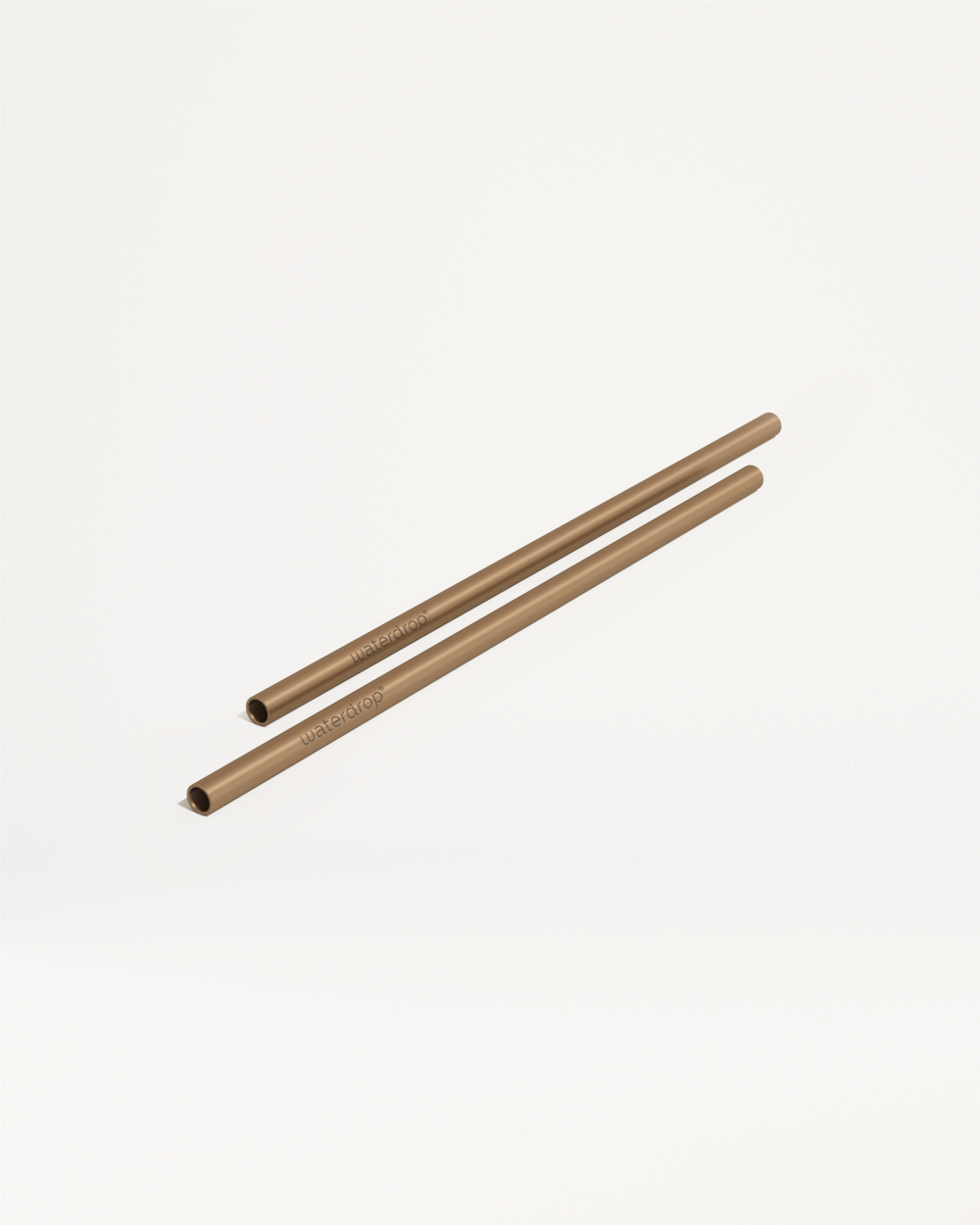Twee bronzen metalen drinkrietjes van waterdrop®, genaamd Kies je goodie, liggen naast elkaar op een witte achtergrond.