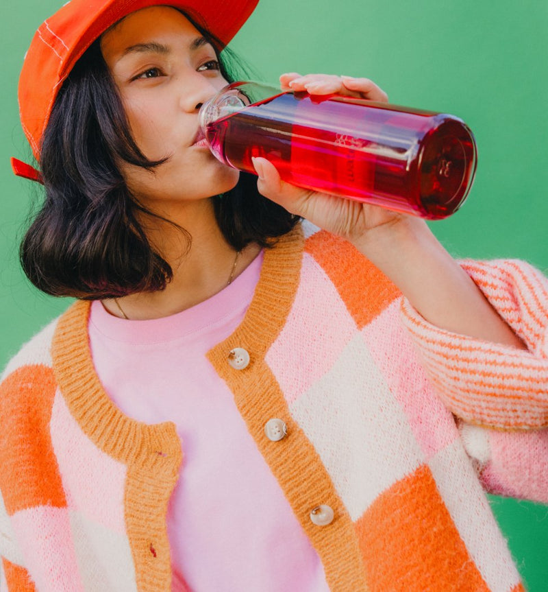 Een vrouw drink een Microdrink uit een doorzichte glazen drinkfles