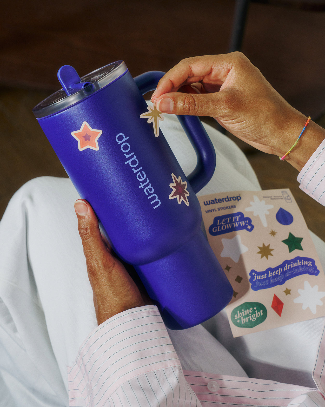 Adventskalenderset van waterdrop®: Een kobaltblauwe reisbeker met handgreep, voorzien van een transparant, morsbestendig deksel, wordt versierd met gouden sterrenstickers. Een perfect cadeau voor de feestdagen.