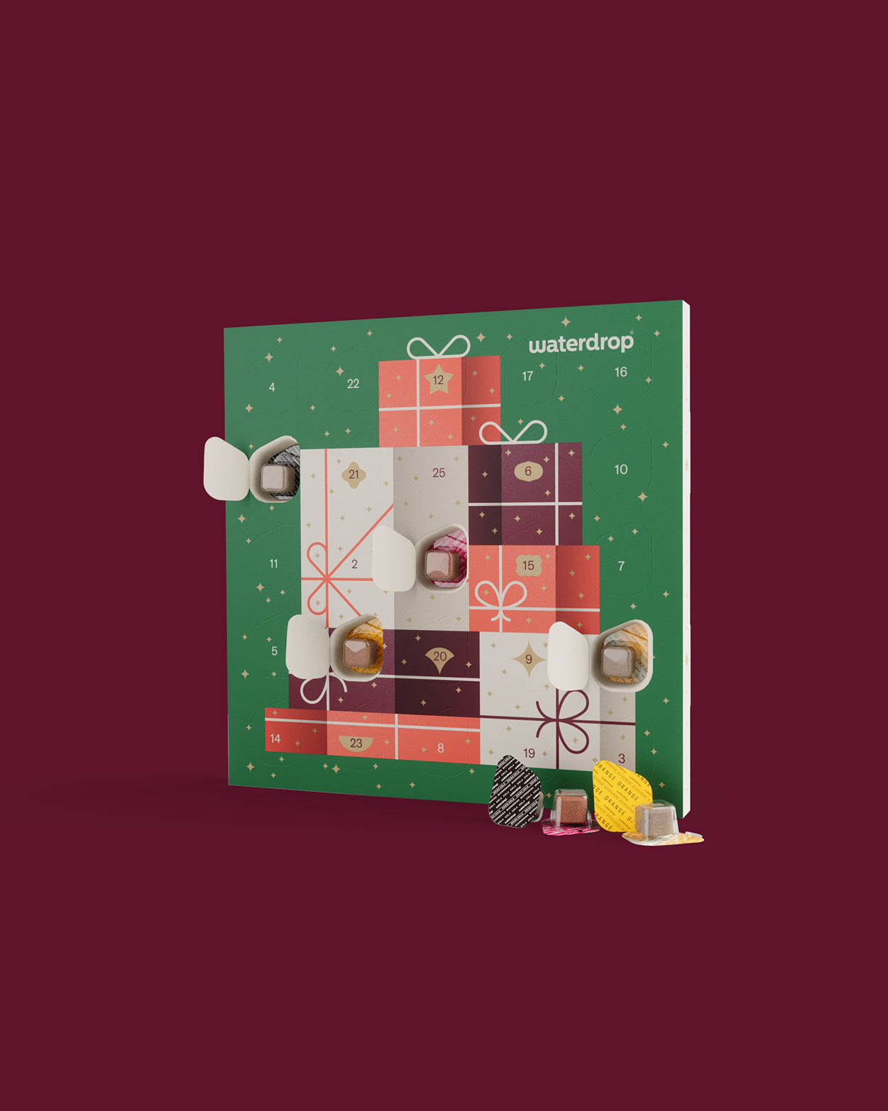 Small adventskalender duopakket van Waterdrop getoond met geopende deurtjes, onthullend microdrinkblokjes in folie. Voor de kalender liggen enkele smaakpods, perfect voor feestelijke hydratatie met geliefde smaken.