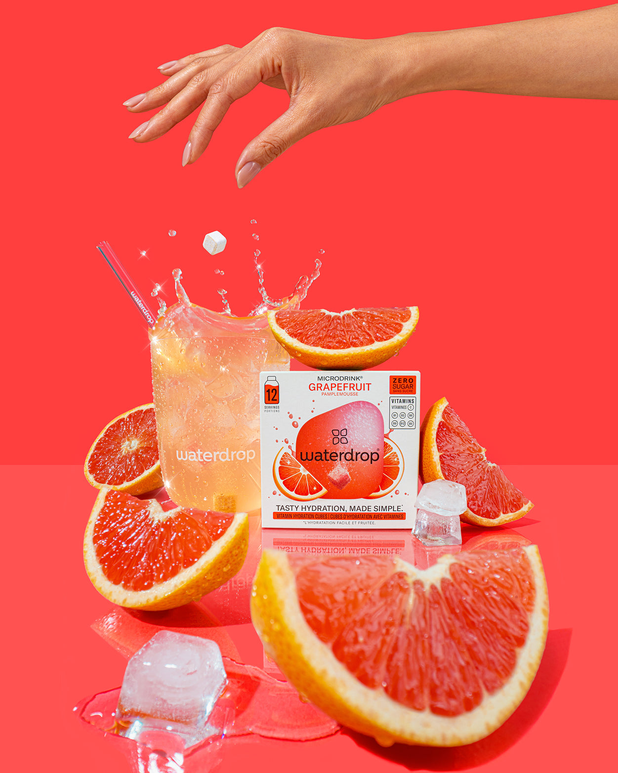 Starterset Glass Deluxe met bruisend water en een waterdrop microdrink van grapefruit, met bijbehorende doos en glazen rietje, omringd door verse grapefruits en smeltende ijsblokjes voor verfrissende hydratatie.