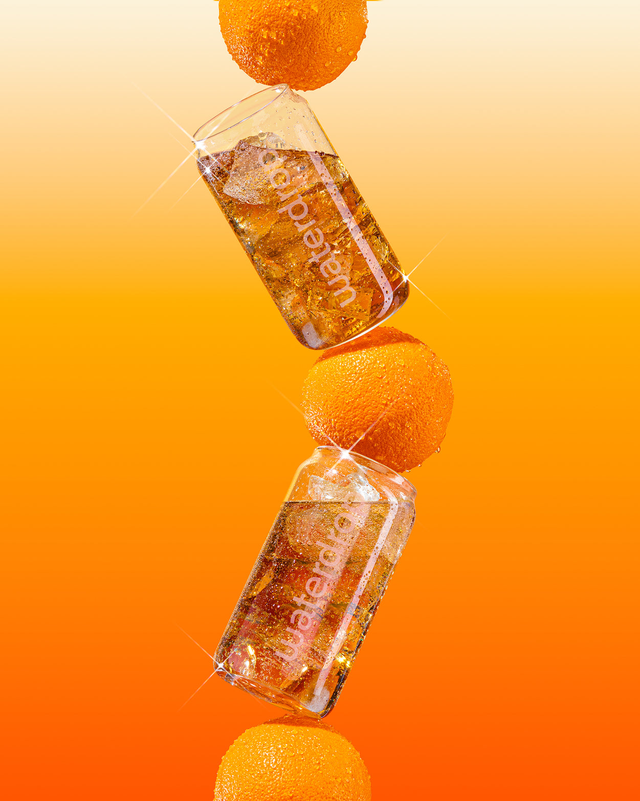 Een verticale stapel van verse sinaasappels en twee flessen met waterdrop-logo tonen de COLA ORANGE 3+1, een sprankelende drank met een limited edition sinaasappel-twist tegen een levendige achtergrond.