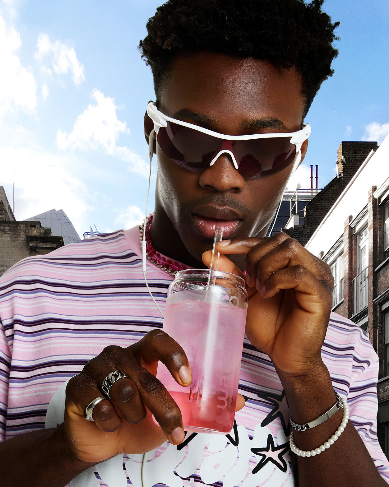 Een persoon geniet van een verfrissend drankje uit de Frisdrankenset van waterdrop®, geserveerd in een glazen pot met rietje, passend bij hun trendy urban stijl.