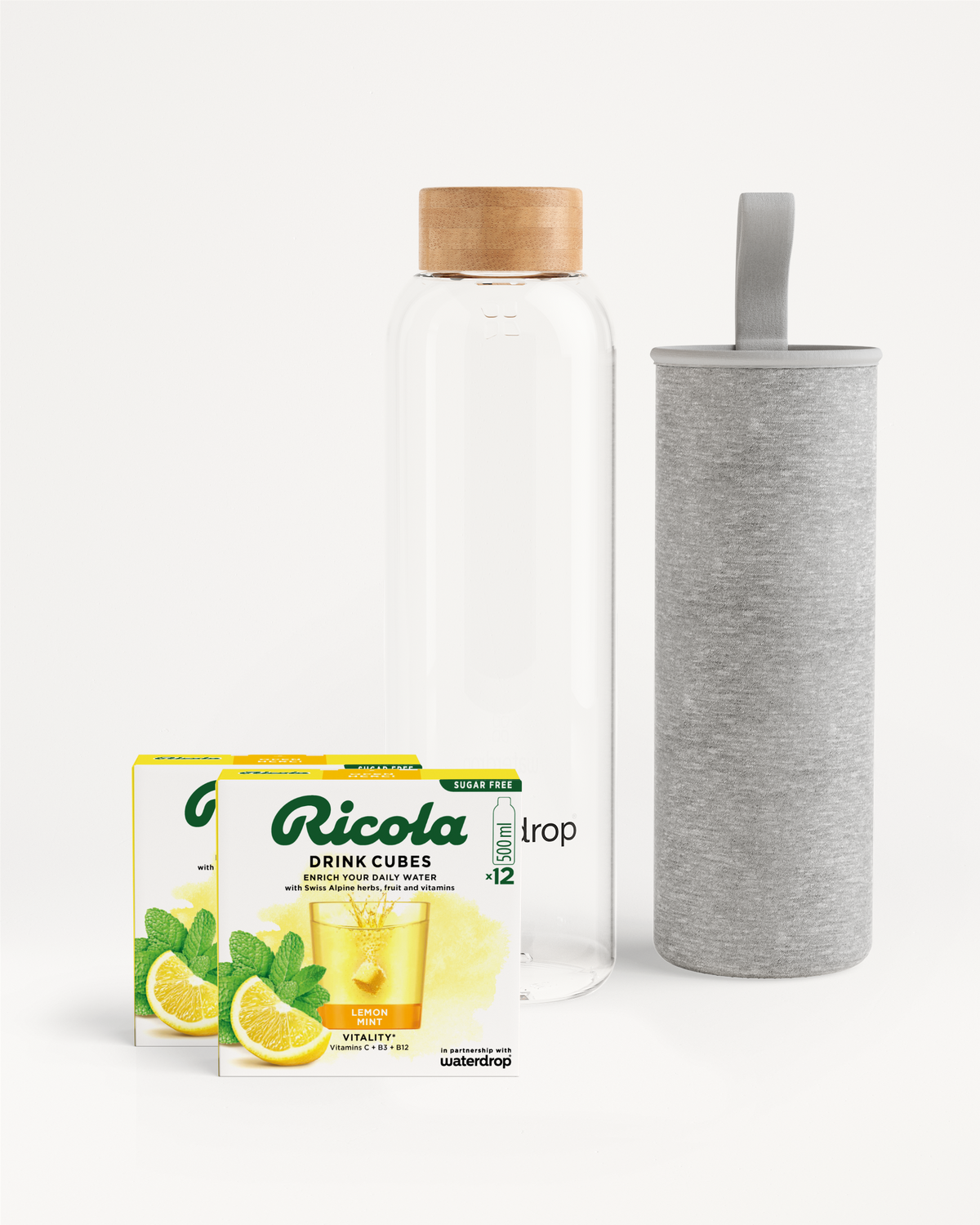 Flessenset van Ricola: Een hoge glazen drinkfles van waterdrop® met bamboedop, grijze neopreen hoes en twee dozen Ricola Drink Cubes (citroen-munt, suikervrij) voor smaakvolle hydratatie met Zwitserse alpenkruiden en vitamines.