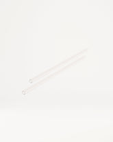 Twee lange, slanke, transparante buisjes, vergelijkbaar met glazen of plastic rietjes, liggen diagonaal. Dit zijn de Explorer Thermo Tumbler Straws, perfect voor waterdrop®'s innovatieve drinkproducten.