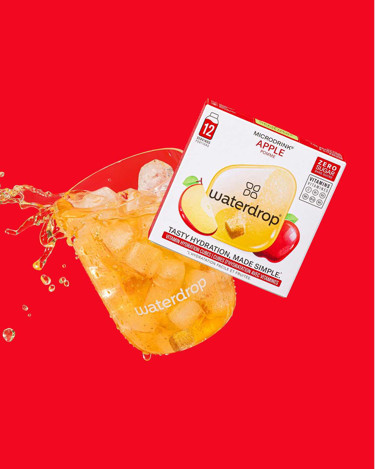 Apple Sparkle Set: een gekantelde doos waterdrop Microdrink Apple hydratatieblokjes met een glas gevuld met ijs en amberkleurige drank, omringd door dynamische spatten, perfect voor suikervrije en caloriearme verfrissing.