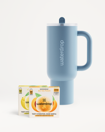 Chill Mode Set: Een poederblauwe waterdrop-tumbler met handvat en heldere deksel, vergezeld van twee doosjes Microdrink: Ice Tea Peach en een citroenvariant. Ideaal voor een suiker- en calorievrije hydratieboost.