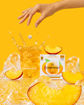 Starter Set Explorer Thermo Drinkbeker: Waterdrop's Ice Tea Peach microdrink zweeft boven een glas met ijs en perzikthee, met verpakking rechts en hand die een kubus toevoegt. Perfect voor onderweg.