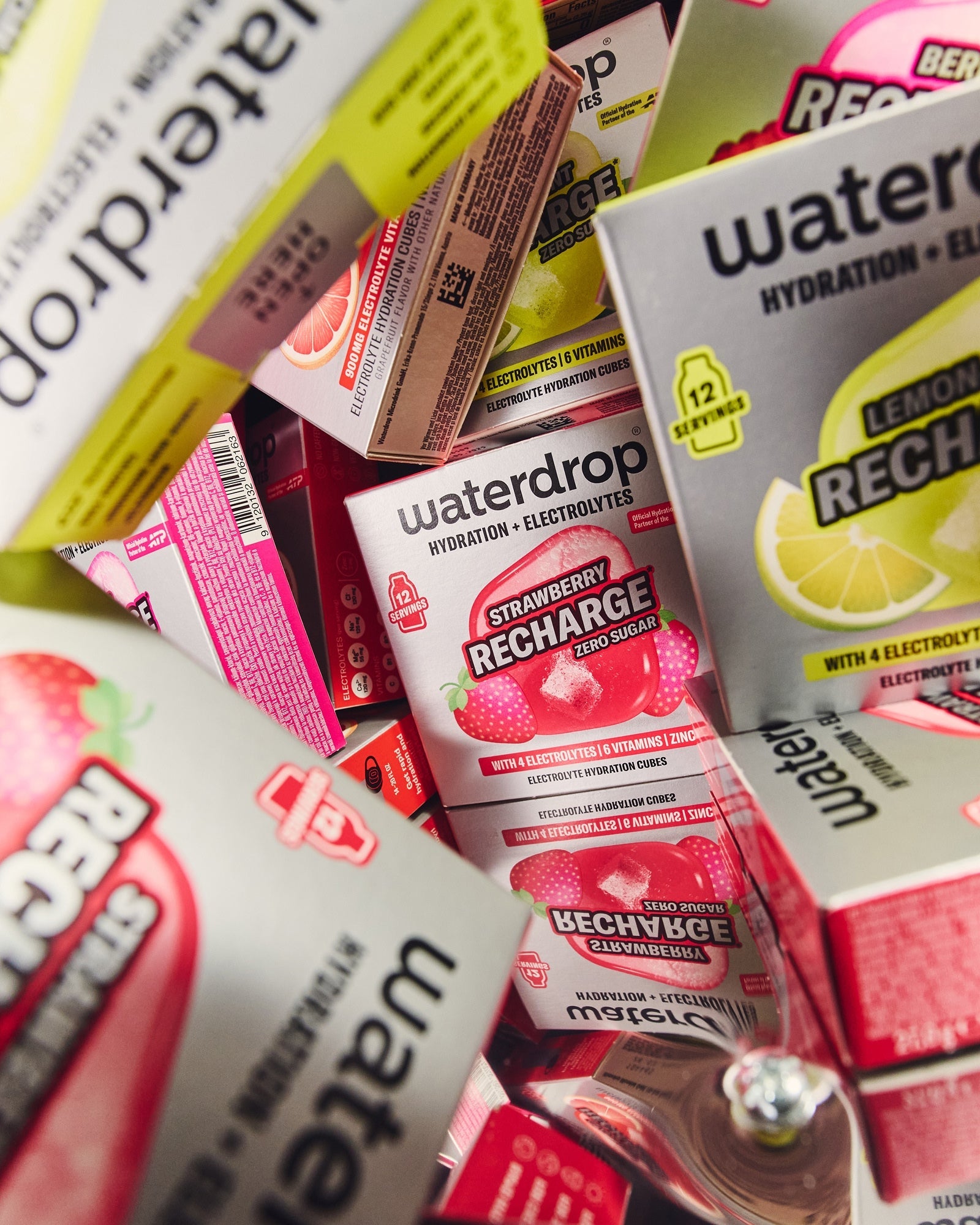 Microlyte RECHARGE Set 3+1: Close-up van diverse hydratatie- en elektrolytenblokjes, met de “Strawberry Recharge” prominent. Inclusief BERRY, LEMON-MINT, en GRAPEFRUIT varianten, allemaal verrijkt met elektrolyten en vitaminen.