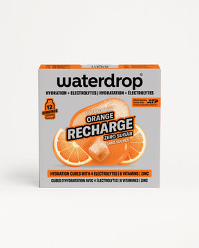 ORANGE RECHARGE retailbox met 12 suikervrije hydratatieblokjes per doos, met sinaasappelsmaak, vier elektrolyten, zes vitamines, en zink. Bilinguale verpakking met ATP-partnerlogo, sinaasappelschijfjes en oplossend blokje zichtbaar.