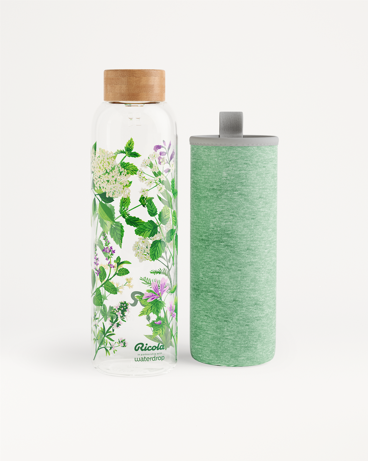 Ricola Edition Glass: Een hoge glazen waterfles met houten dop, bedrukt met kruidenillustraties, naast een bijpassende groen stoffen hoes met draaglus, speciaal ontworpen voor frisse hydratatie in samenwerking met waterdrop®.