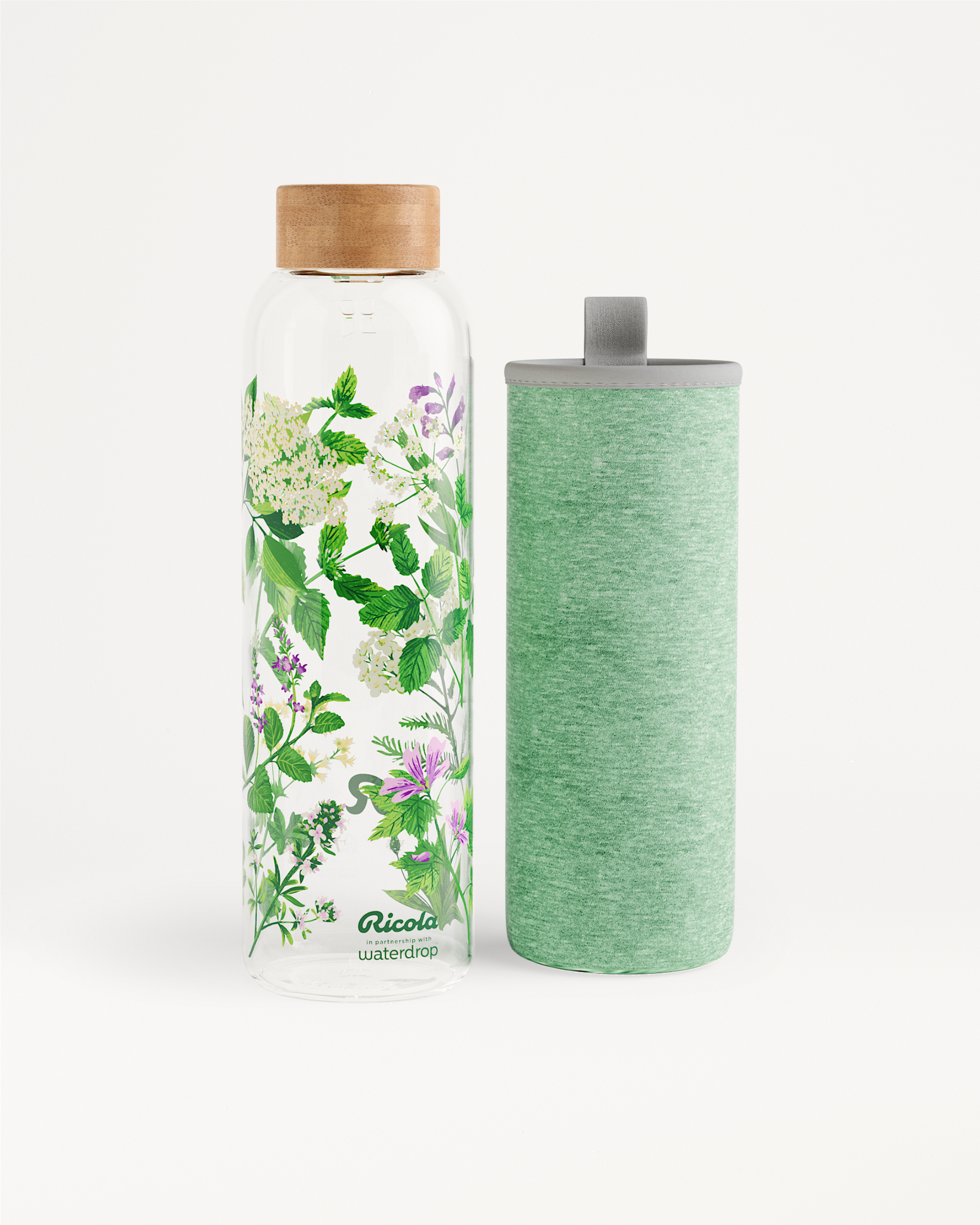 Ricola Edition Glass: Een hoge glazen waterfles met houten dop, bedrukt met kruidenillustraties, naast een bijpassende groen stoffen hoes met draaglus, speciaal ontworpen voor frisse hydratatie in samenwerking met waterdrop®.