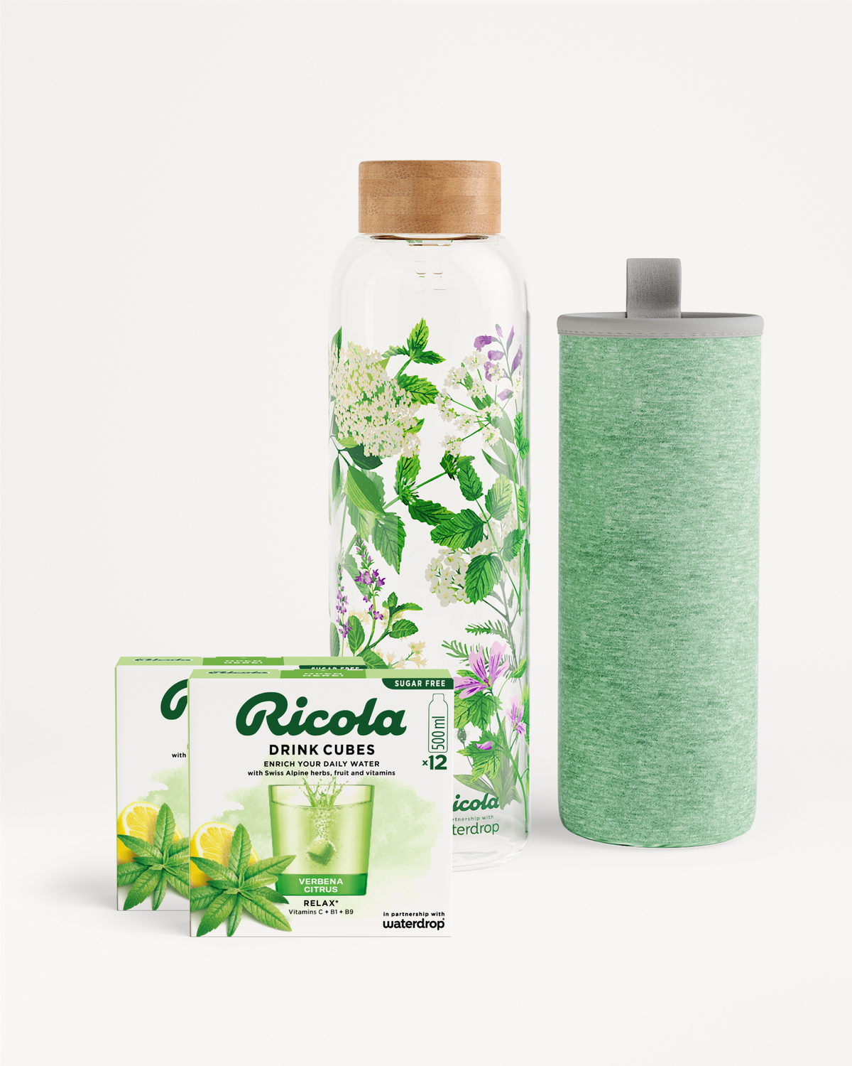 Ricola Bottle Set: Een glazen fles (500 ml) met groene en paarse alpenkruidenprint, een zachtgroene isolatiehoes en twee doosjes Ricola Drink Cubes (Verbena Citrus) voor suikervrije hydratatie.