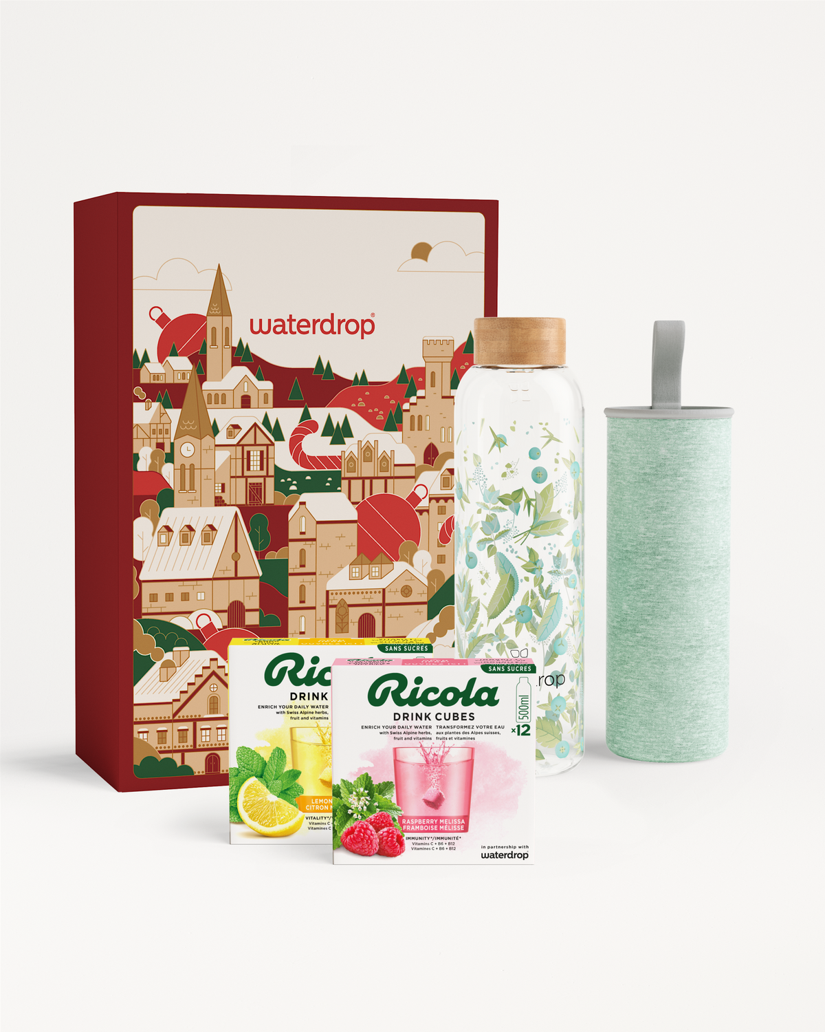 Cadeauset met Ricola en glazen fles: een decoratieve geschenkdoos met twee Ricola Drink Cubes (citroen, framboos), een glazen fles met bamboedop en een mintgroene geïsoleerde hoes met draagriem.