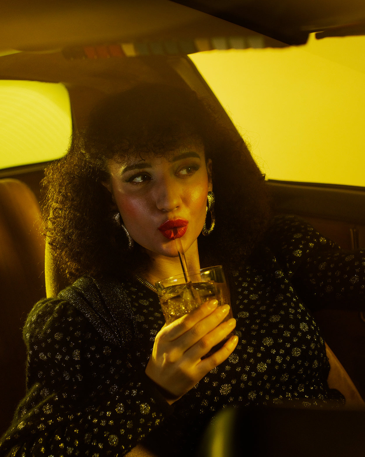 Een vrouw nipt van een drankje in een auto, genietend van de energieboost van het TURBO BOOST duopakket, perfect voor lange dagen en avonden, kenmerkend voor waterdrop®'s suikervrije Microenergy-blokjes.