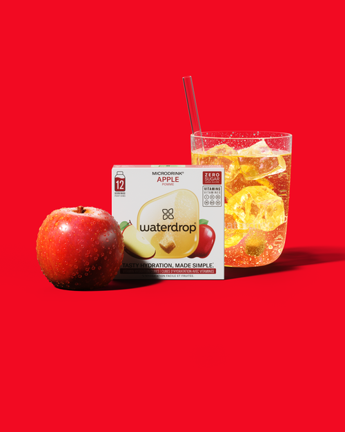 APPEL: Een doos waterdrop® Microdrink met frisse appelsmaak naast een glas ijs en een appel. Geproefd en goedgekeurd, perfect om je water overal smaak te geven.