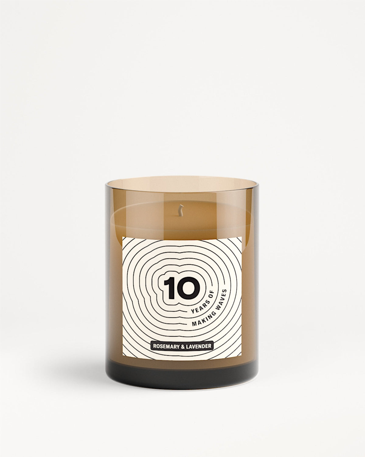 Bruine glazen kaars in pot met wit label en ontwerp met concentrische cirkels.