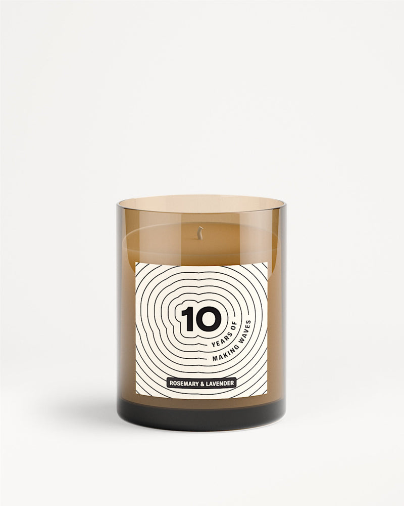 Bruine glazen kaars in pot met wit label en ontwerp met concentrische cirkels.