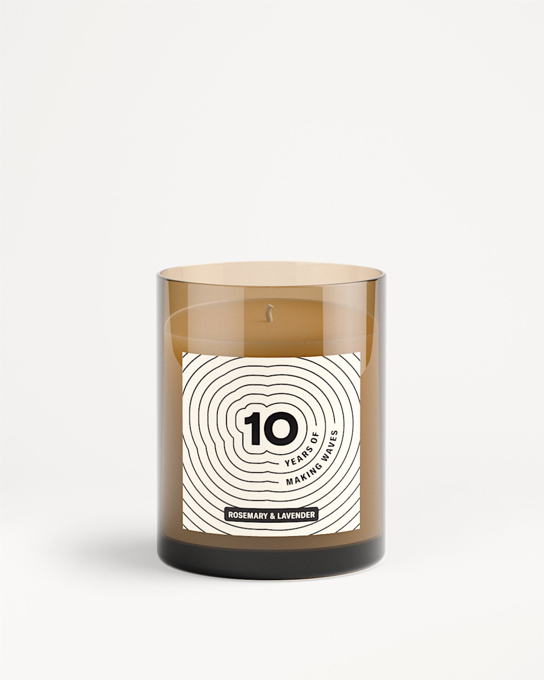 Bruine glazen kaars in pot met wit label en ontwerp met concentrische cirkels.