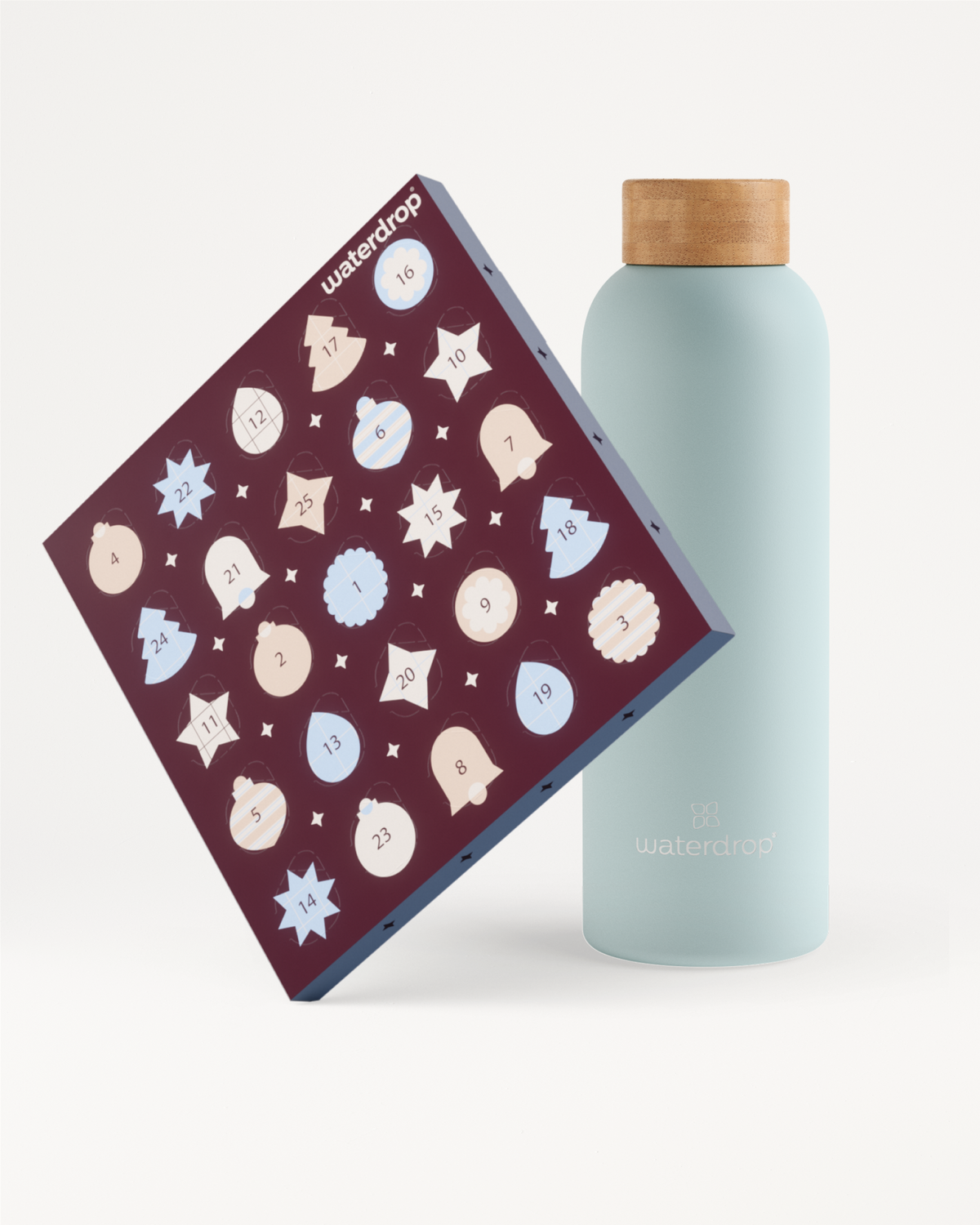 Lichtblauwe herbruikbare fles met houten dop naast een paarse adventskalender met witte en lichtblauwe sneeuwvlokken.