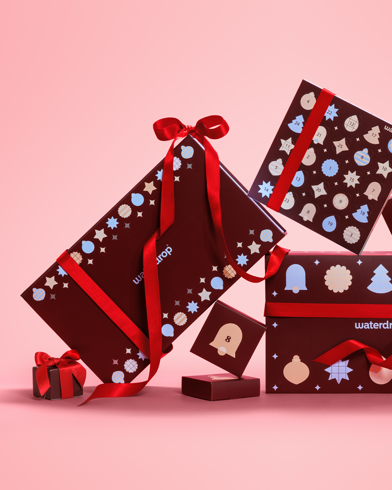 Ingepakte cadeaus met rode linten en feestelijke patronen op een roze achtergrond.