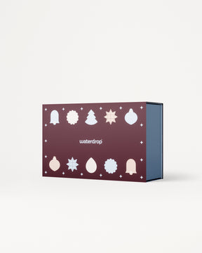 Paars cadeauverpakking met witte kersticonen op dedeksel en een blauwe binnenkant.