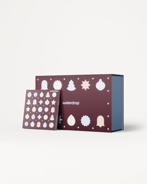 Adventskalender met paarse panelen en witte kerstornamenten, getoond met een blauwe binnenkant doos.