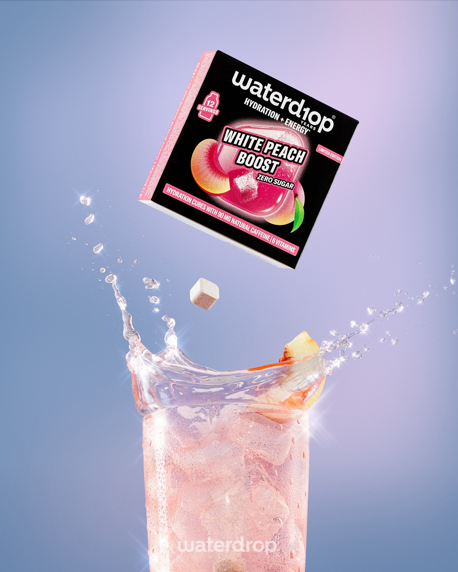 Doos White Peach Boost-drankmix zweeft boven een hoog glas met een roze drankje en ijs.
