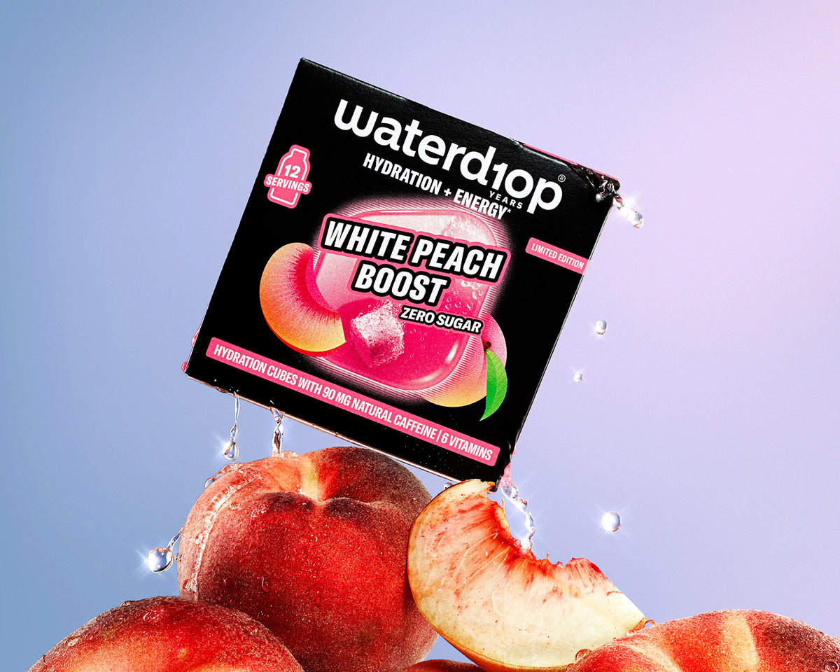 Verkocht hydraterende en energiedrankbox op een stapel perziken met druppels water, roze-blauw verloop op de achtergrond.