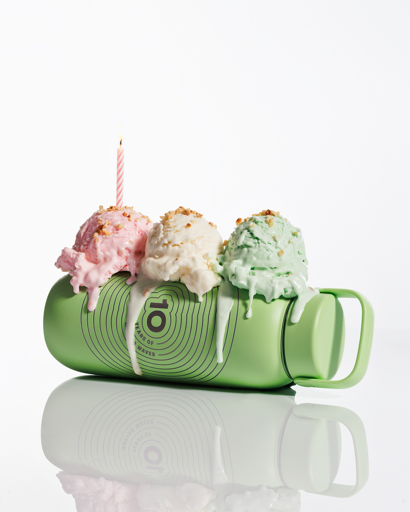Groene beker liggend met drie bolletjes ijs bovenop en een brandende kaars, smeltende glazuur druppelt naar beneden.