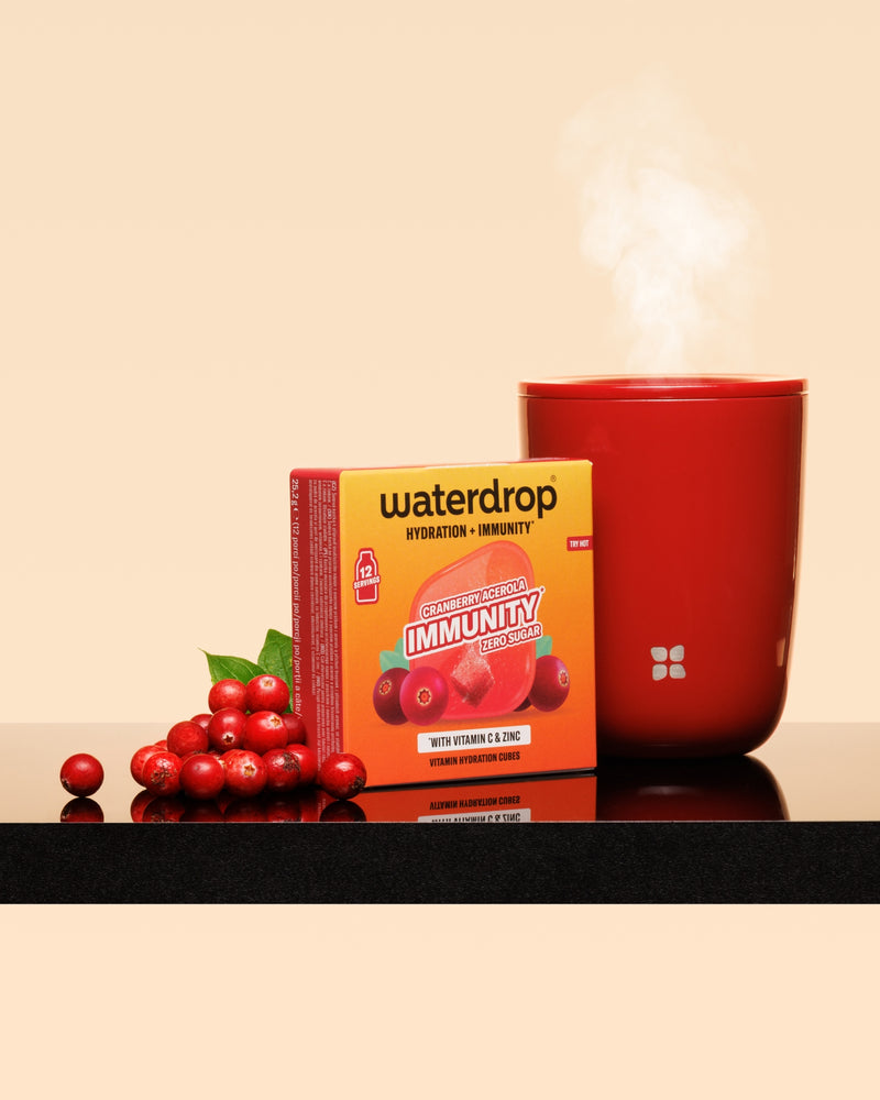 Rode dampende kop naast een rode doos en een tros cranberries op een glanzend oppervlak.