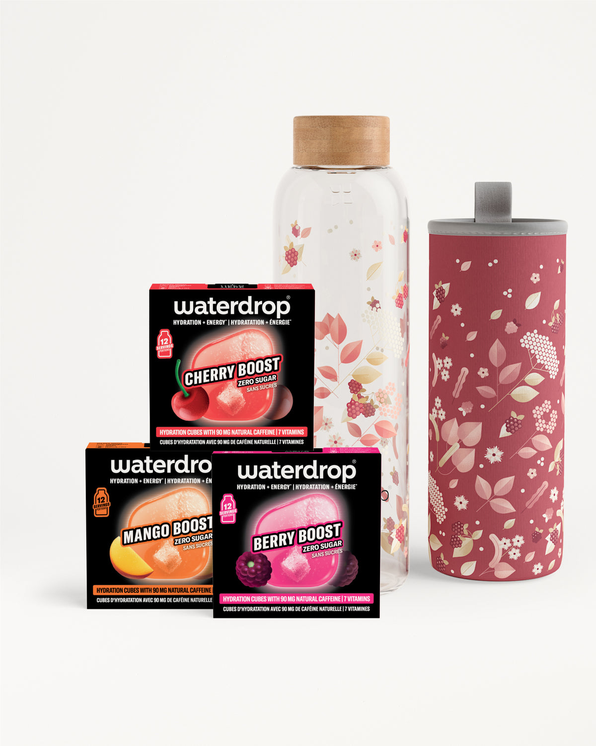 Assortiment van drie smaakboost-zakjes naast een glazen fles met houten dop en een hoge roze bloemige tumbler.