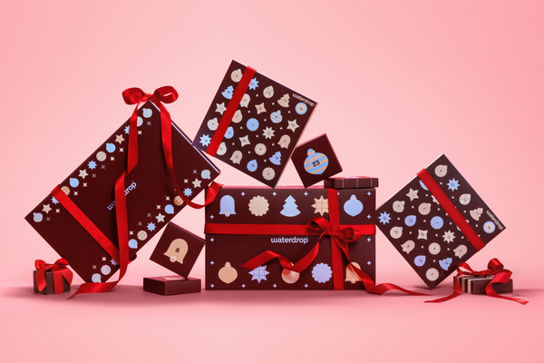 Verschillende cadeauverpakkingen in donker papier met rode linten op roze verloopachtergrond.