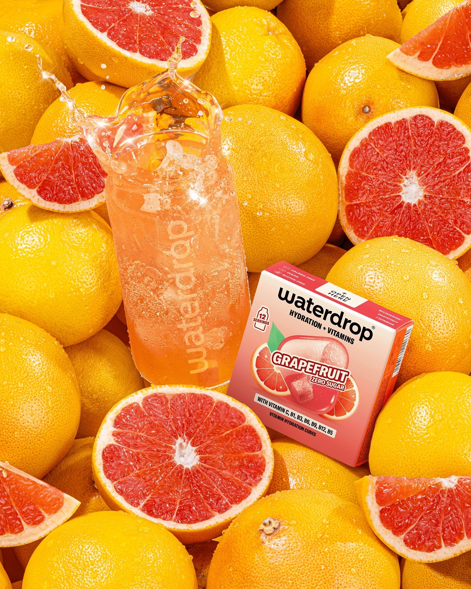 Assortiment grapefruit met een fles roze grapefruitdrank en een kleine doos tussen het fruit.