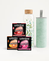 Set van drie Waterdrop Flavor Boost-doosjes met een glazen infusiebottle en een lichtgroene beker.