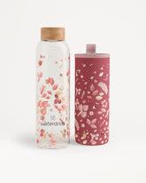 Twee waterflessen met een bloemenpatroon, een heldere fles met houten dop en een roze fles met bijpassende dop.