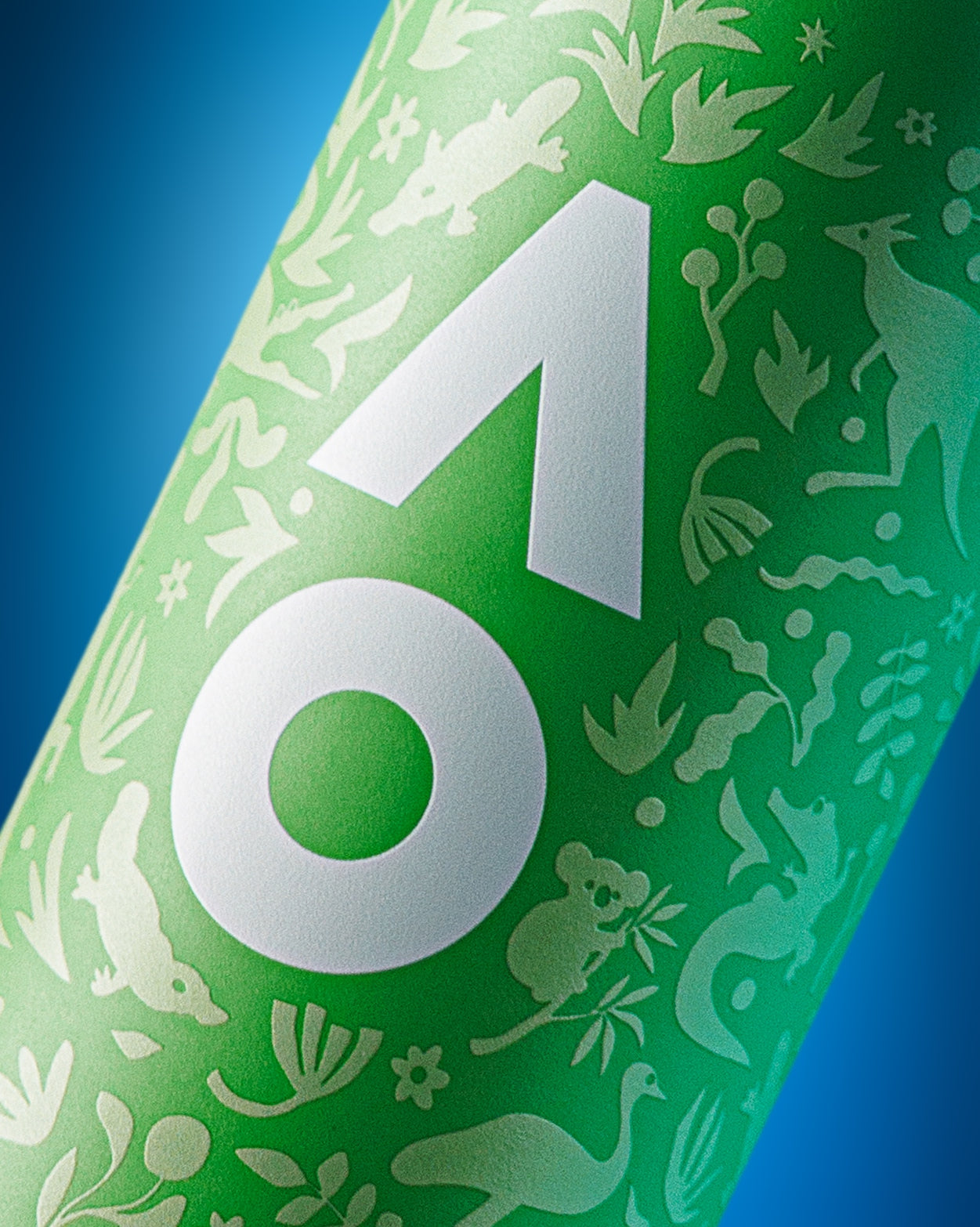 Close-up van een groene, cilindrische fles met een groot wit geometrisch embleem en decoratieve witte silhouetten tegen een blauwe achtergrond.