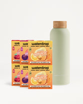 Zes oranje drankmixer-doosjes naast een lichtgroene fles met kurkendop.