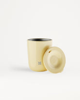 Beige tumbler met bijpassende deksel naast elkaar.