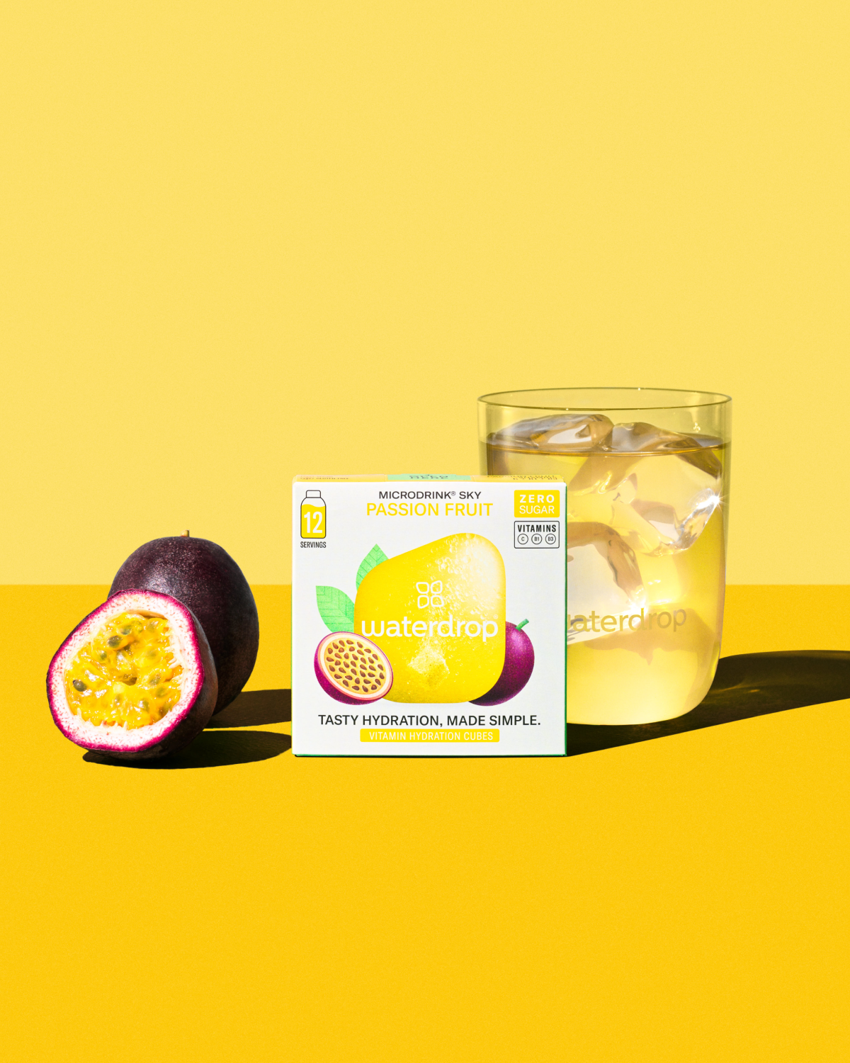 Exclusieve set waterdrop® x Ricola: een halve passievrucht, een doosje Sky Passion Fruit Microdrink® en een glas met ijs en drank, benadrukken de frisse, fruitige hydratatie-ervaring zonder suiker en calorieën.