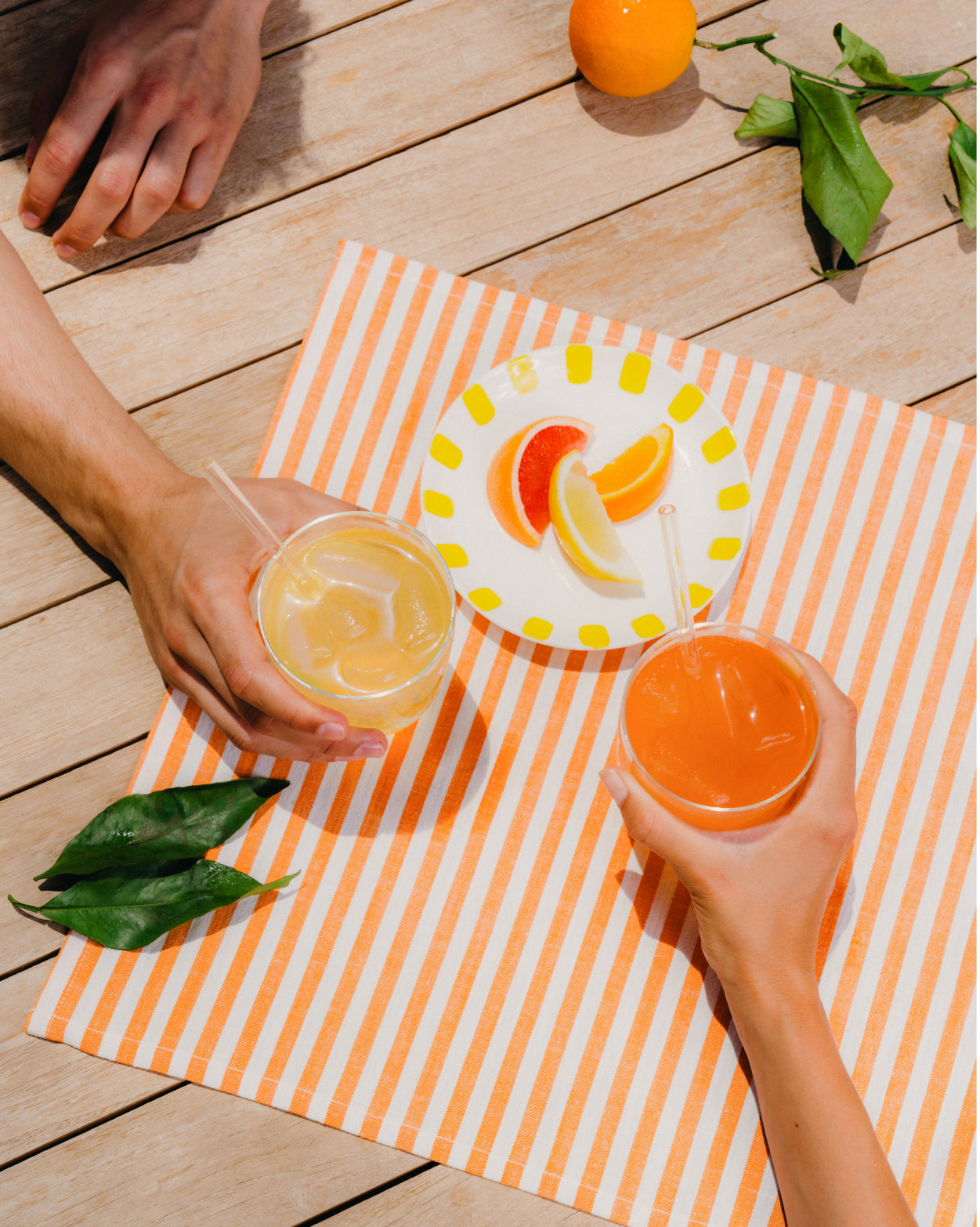 Zomer Bestseller Set: Een hand houdt een glas oranje sap, symbool van de verfrissende smaken van sinaasappel, grapefruit en de Limited Edition Paradise en Wildberry Fusion van waterdrop® NL.
