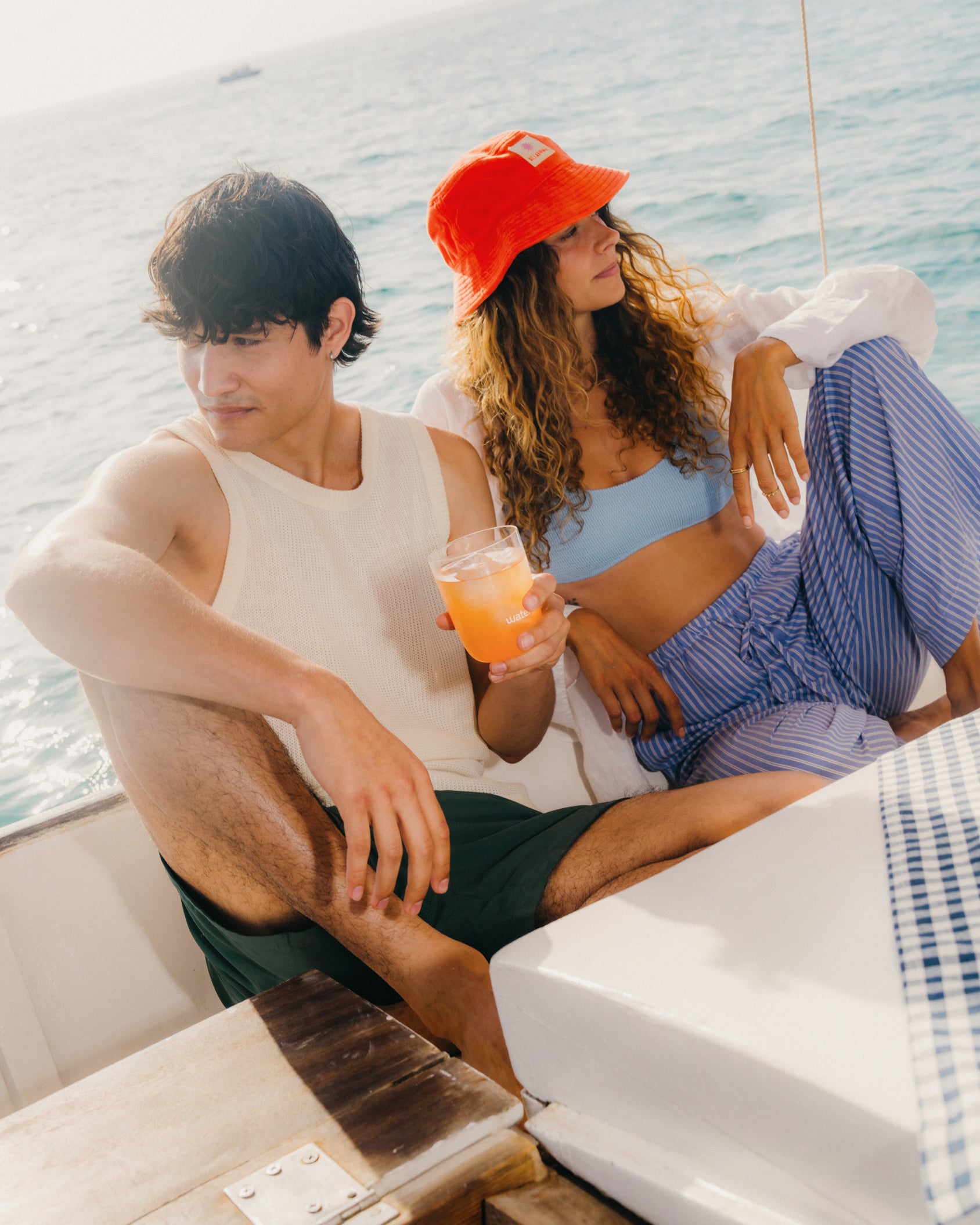 Zomer Bestseller Set: Een man en vrouw op een boot genieten van een glas, met de exclusieve set die de smaken Sinaasappel, Grapefruit, Paradise en Wildberry Fusion van waterdrop® viert.