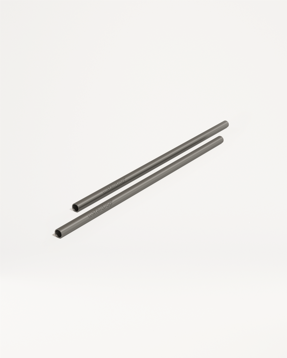 Twee slanke, grijze, herbruikbare metalen rietjes met het merk “waterdrop” zichtbaar, onderdeel van de Kies je goodie collectie van waterdrop® NL, liggend op een witte ondergrond.